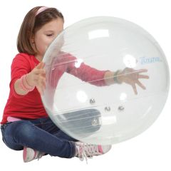 A girl plays with a large transparent ball with bells inside to hear the sound